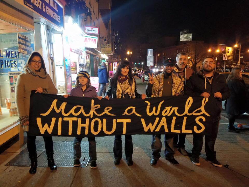 A group holds a sign saying "Make a world without walls"